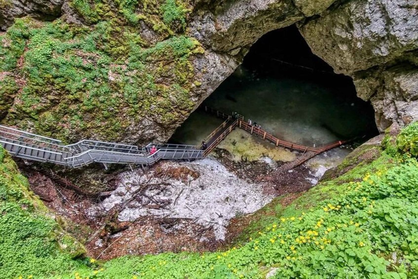 A cave entrance with a metal staircase leading down. 1
