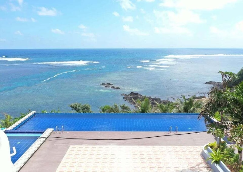 A pool with a view of the ocean and rocky outcrops. 5