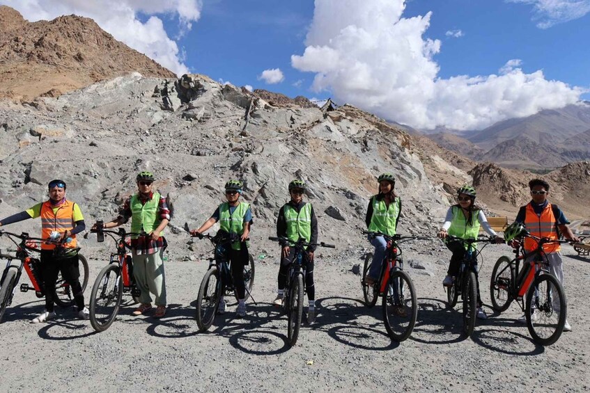A group of cyclists on a mountain trail with rocky terrain and distant mountains. 1