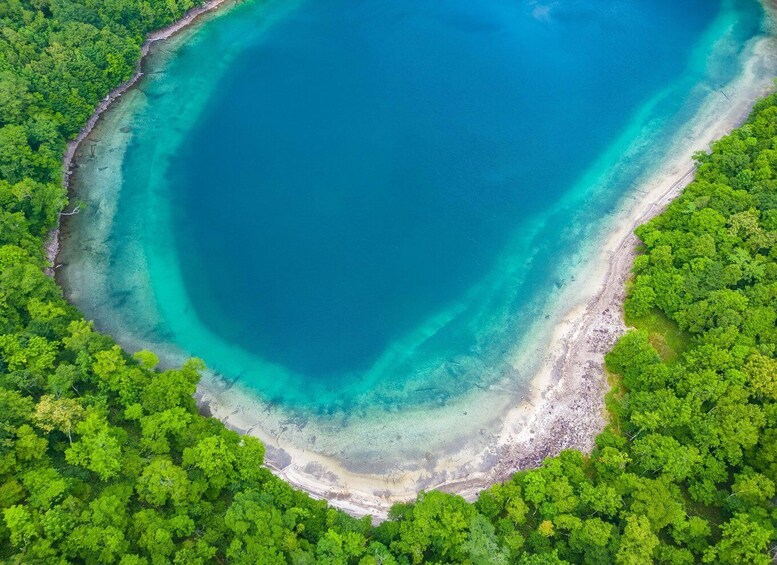 An aerial view of a turquoise lagoon surrounded by dense green forest. 2