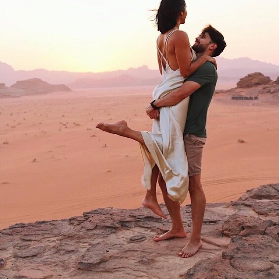 A couple embracing on a rocky outcrop with a desert landscape in the background. 1