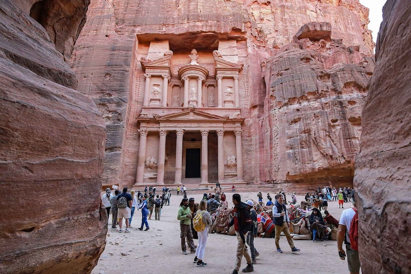 A group of people at Petra's Treasury, surrounded by sandstone cliffs. 4