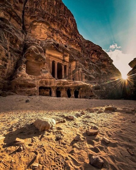 A rock-cut temple with columns and a desert landscape. 2