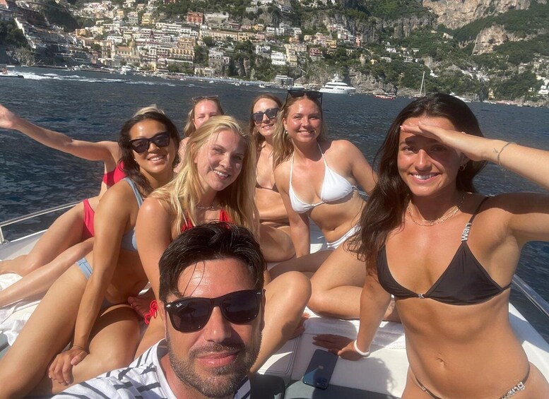 A group of people on a boat with a coastal town in the background. 1