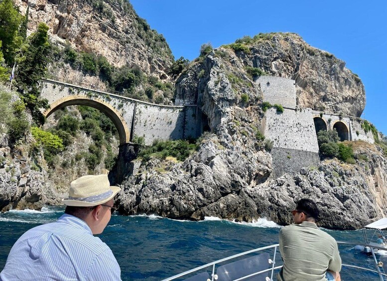 A stone bridge over water, rocky cliffs, and a boat. 2