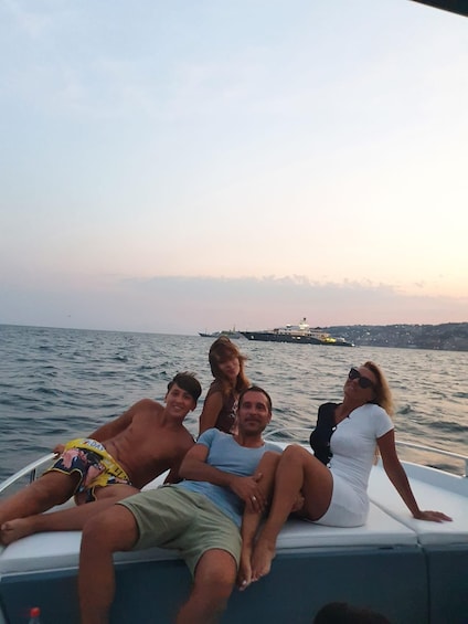 A group of people on a boat with a ship in the background. 5