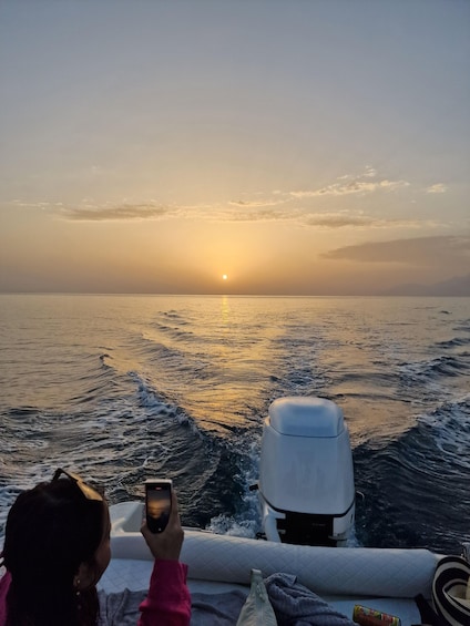 A person taking a photo of a sunset over the ocean. 3