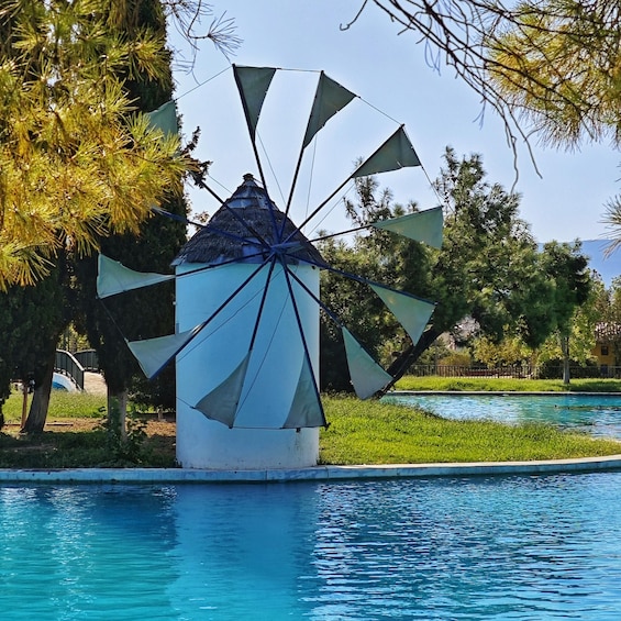 A windmill with a white base and blue roof, surrounded by trees and a swimming pool. 1