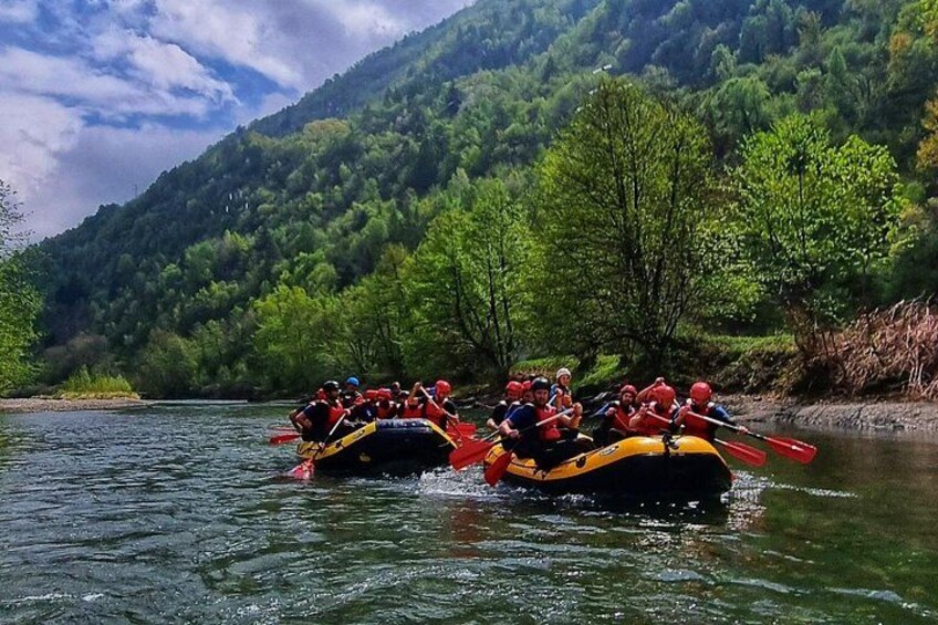 A group of people rafting on a river surrounded by lush green hills. 4