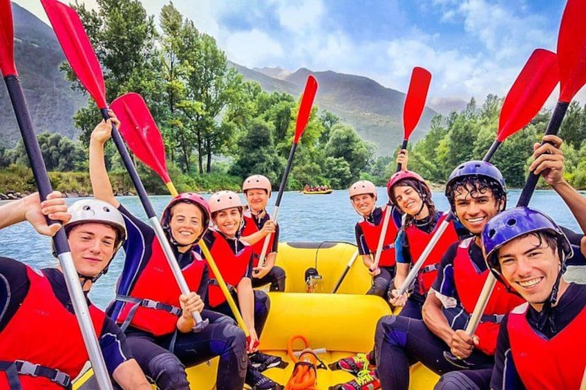 A group of people in a yellow raft on a river, wearing life jackets and helmets, with mountains in the background. 3
