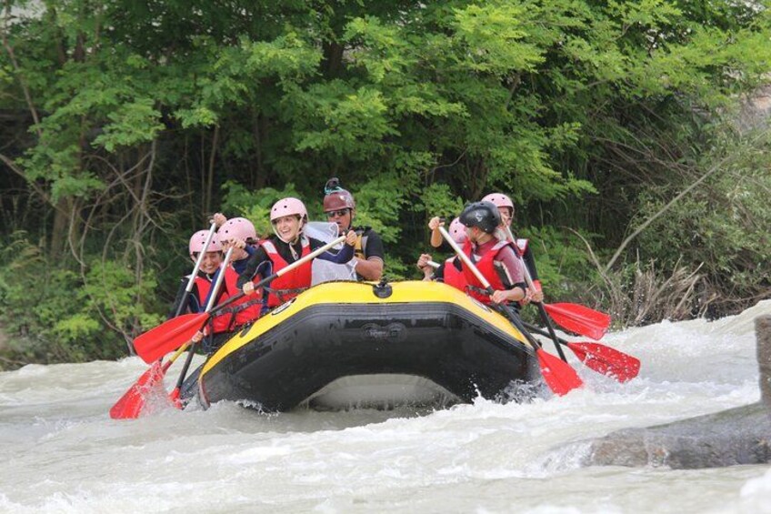 A group of people in a raft navigating a river surrounded by dense greenery. 1