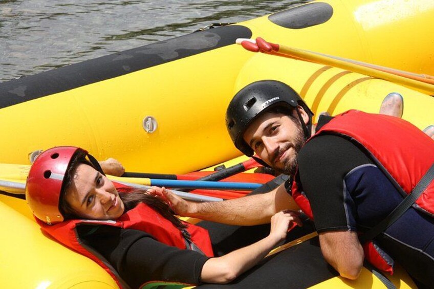 Two people in a yellow inflatable raft, wearing helmets and life jackets. 2