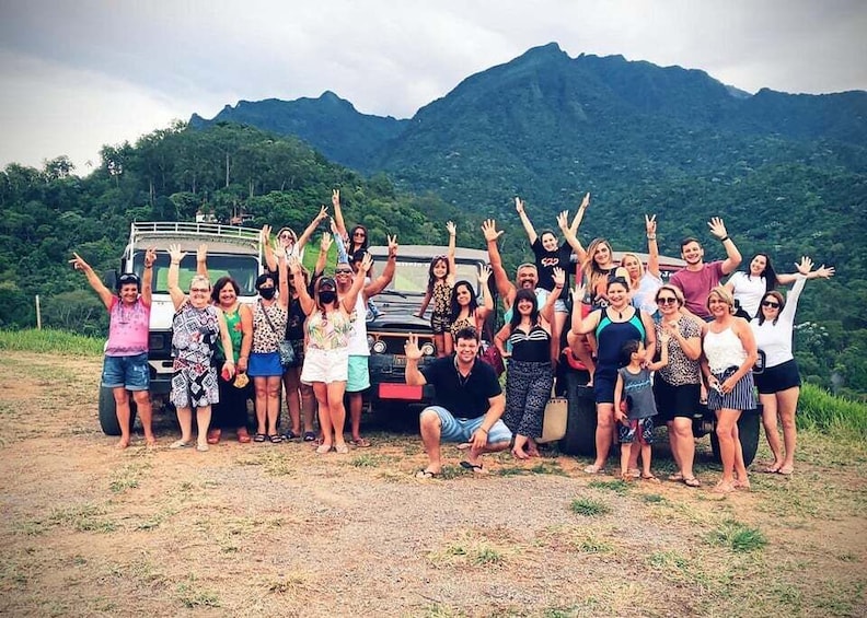 A group of people posing with a vehicle in a mountainous area. 2