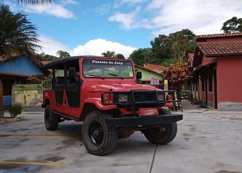 A red Jeep with 'Passeio de Jeep' written on the windshield parked in a street. 4