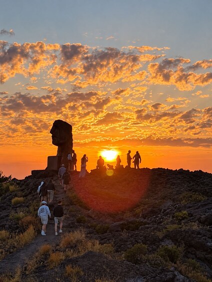 Solnedgang med en gruppe mennesker stående på en klippe. 2