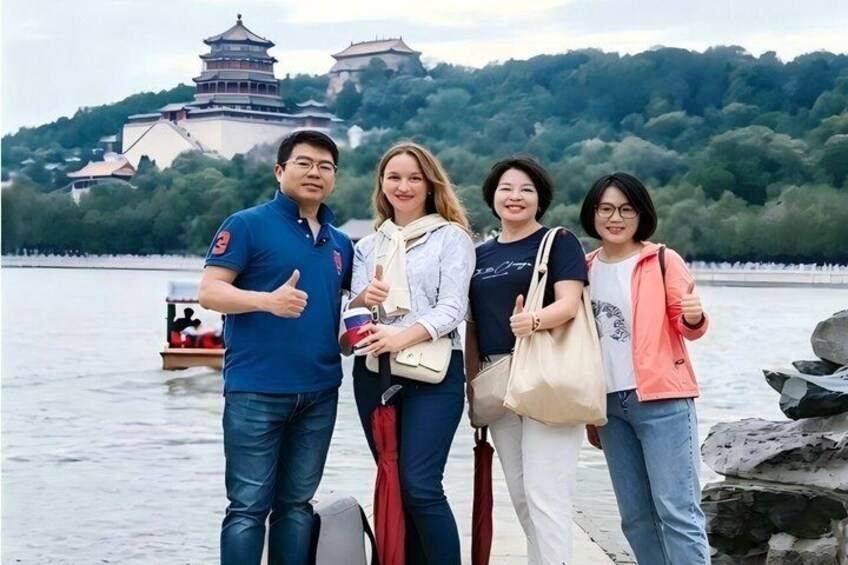 A group of people standing by a lake with a traditional pagoda in the background. 1