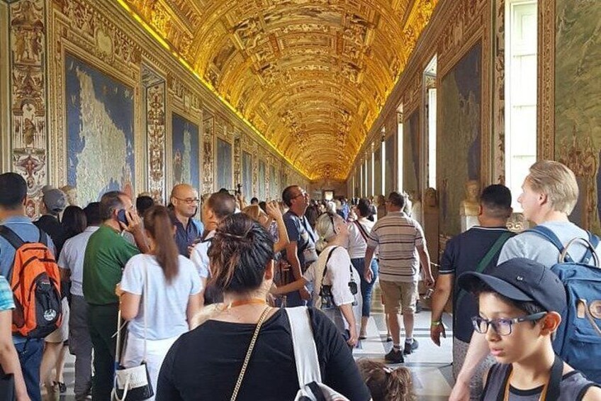 A crowded hallway with ornate golden decorations and columns. 2