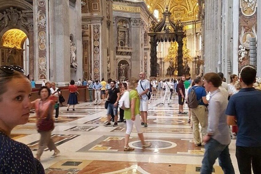 A crowded interior of a historic building with ornate columns and a central altar. 5