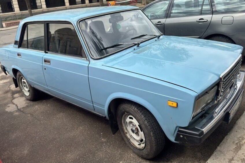 A light blue vintage car parked on a street. 2