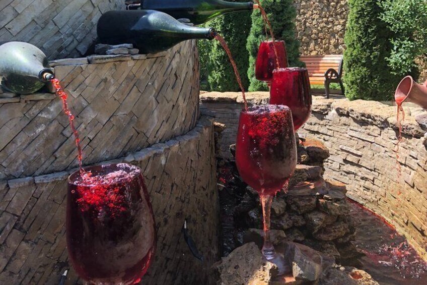 Wine glasses filled with red wine, a stone wall, and a rustic outdoor setting. 1