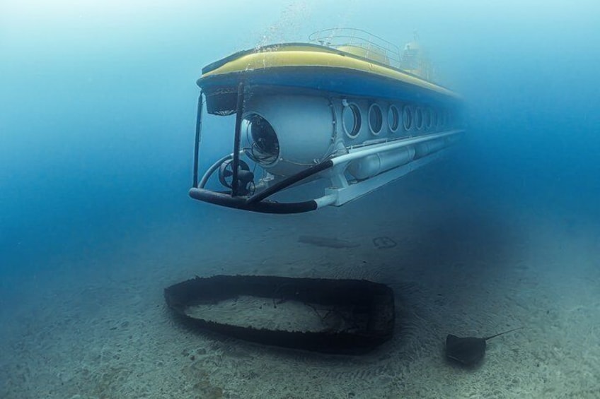 An underwater submersible vehicle with a yellow and blue exterior, a large circular window, and a propeller at the front. 2
