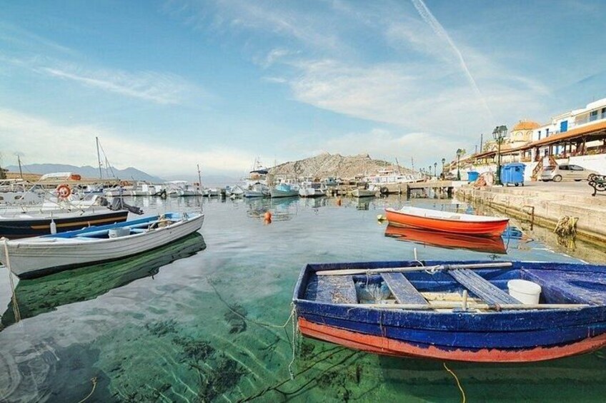 A harbor with boats docked, clear water, and a distant mountain. 2