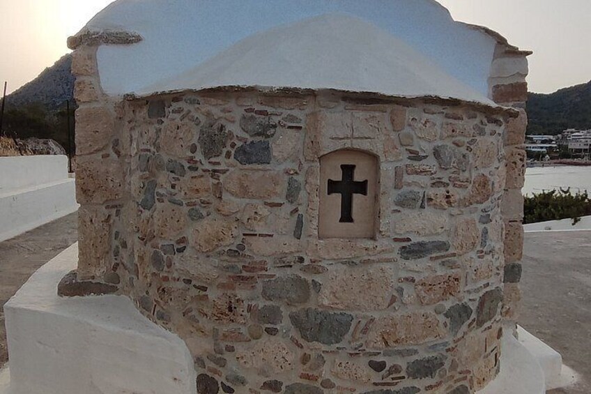 A stone structure with a cross emblem, surrounded by white concrete blocks. 4