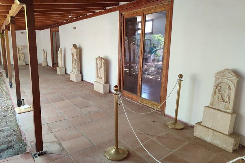 A covered walkway with stone statues and a glass door leading to an outdoor area. 4