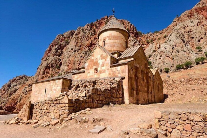 A small stone church with a dome, surrounded by rocky terrain and a clear blue sky. 2