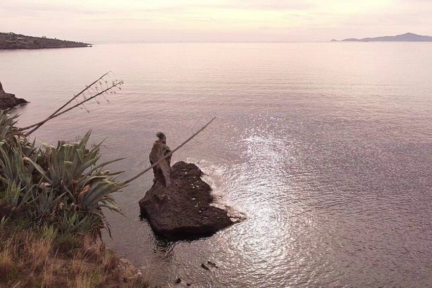 A rocky outcrop in a body of water with a distant shoreline. 3