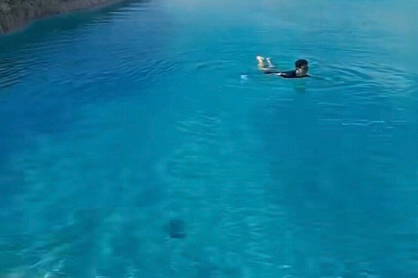 A person swimming in a clear blue body of water. 2