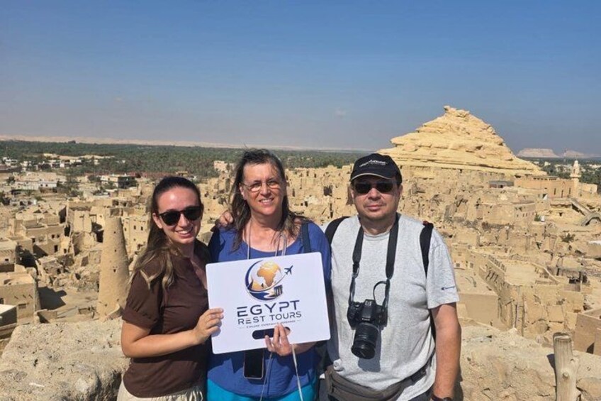 Three people standing in front of ancient ruins with a pyramid in the background. 5