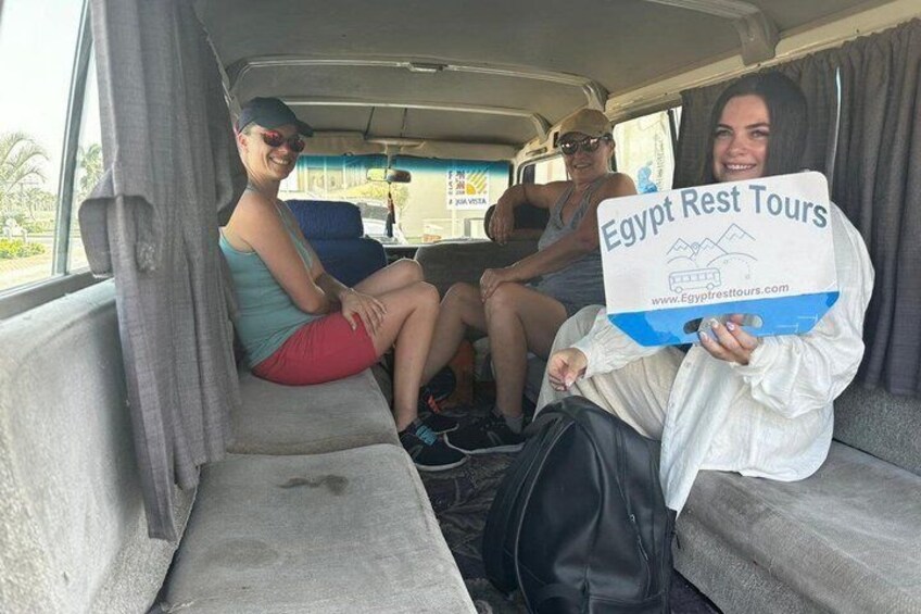 A vehicle interior with people holding a sign for Egypt Rest Tours. 1