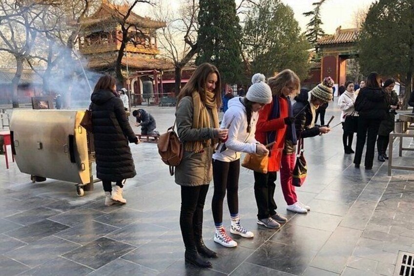 A group of people standing outdoors, a traditional building, and a large metallic structure. 2