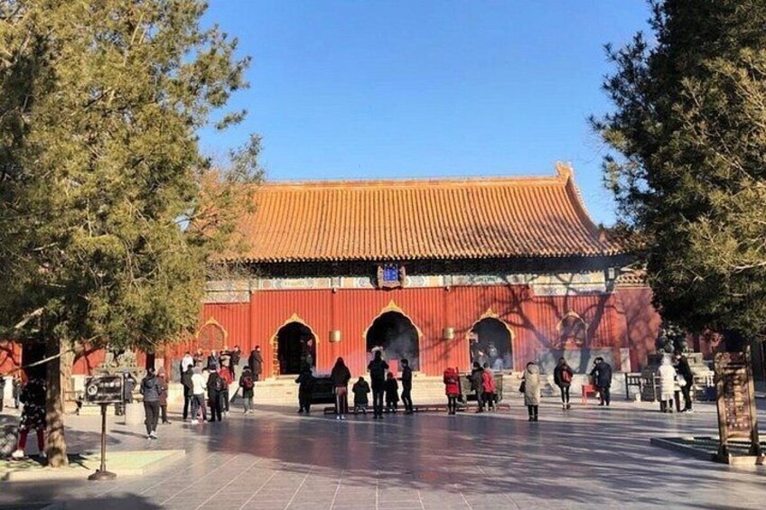 A traditional Chinese building with a tiled roof, surrounded by trees and people. 3