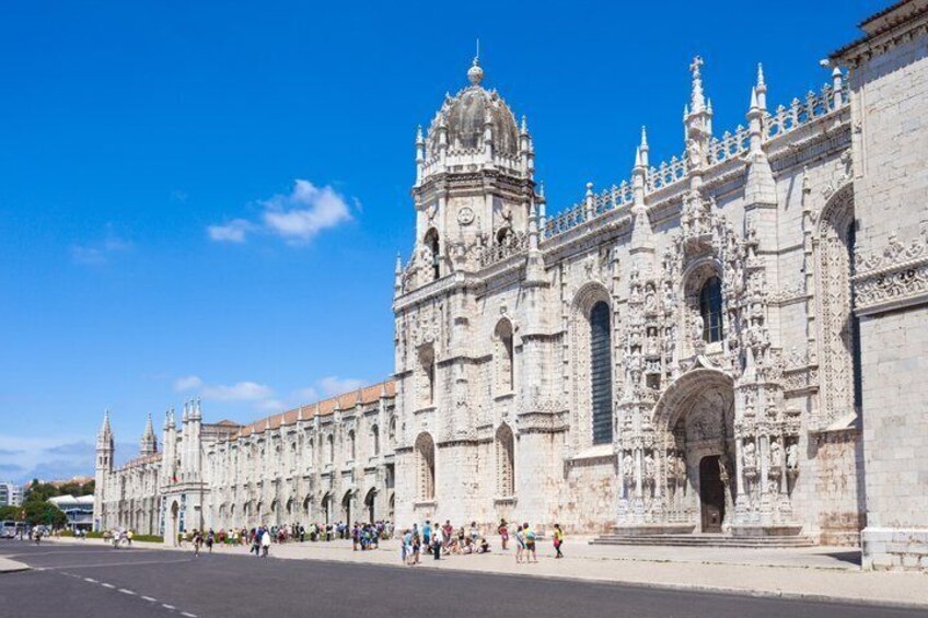 A large, ornate historical building with intricate architectural details and a clear blue sky. 1