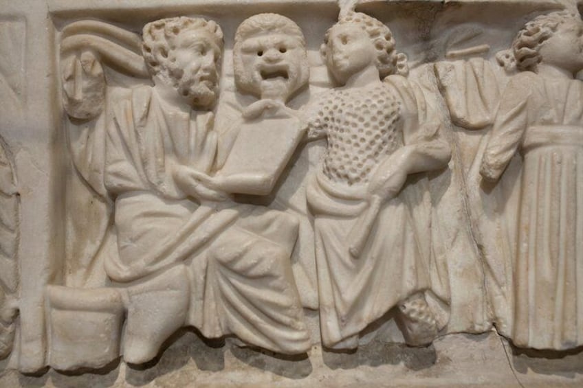 A stone relief sculpture with figures in draped garments, possibly depicting a historical or mythological scene. 2