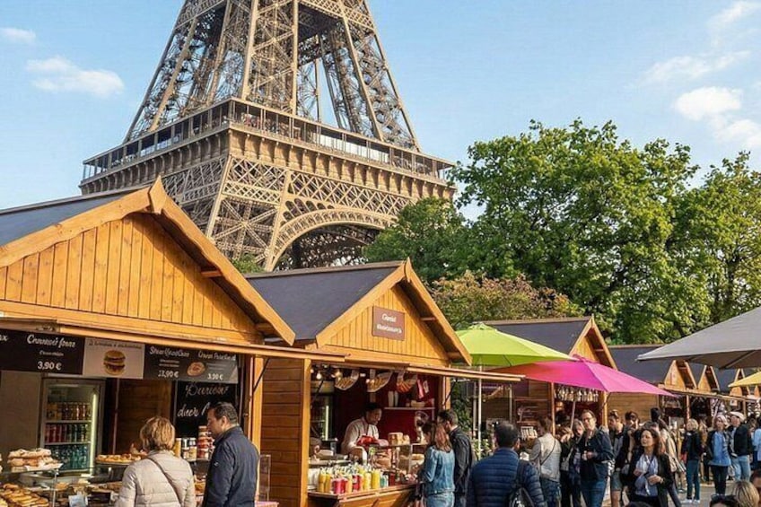 The Eiffel Tower, a market with wooden stalls, and people shopping. 5