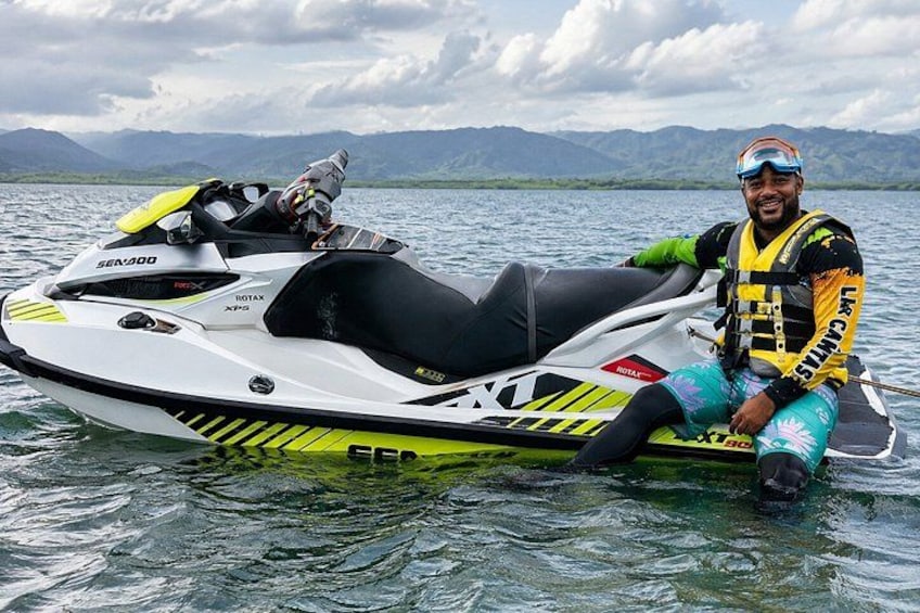 A person sitting on a Sea-Doo jet ski on a lake with mountains in the background. 3