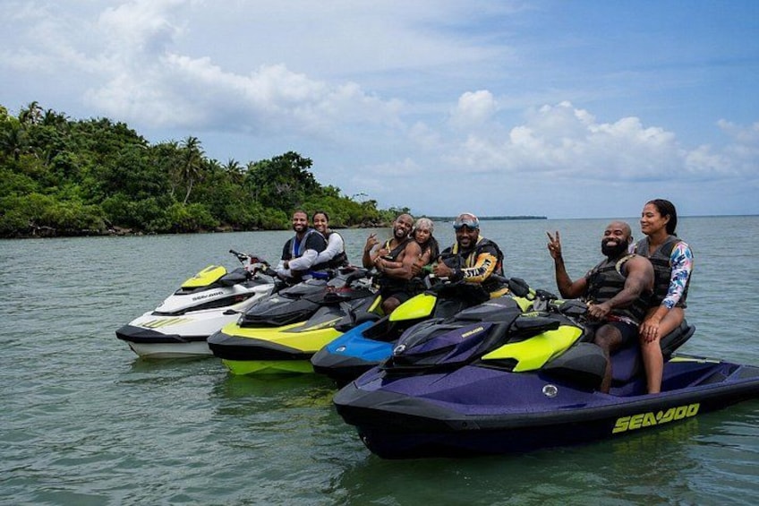 A group of people on jet skis on calm water with a forested island in the background. 2