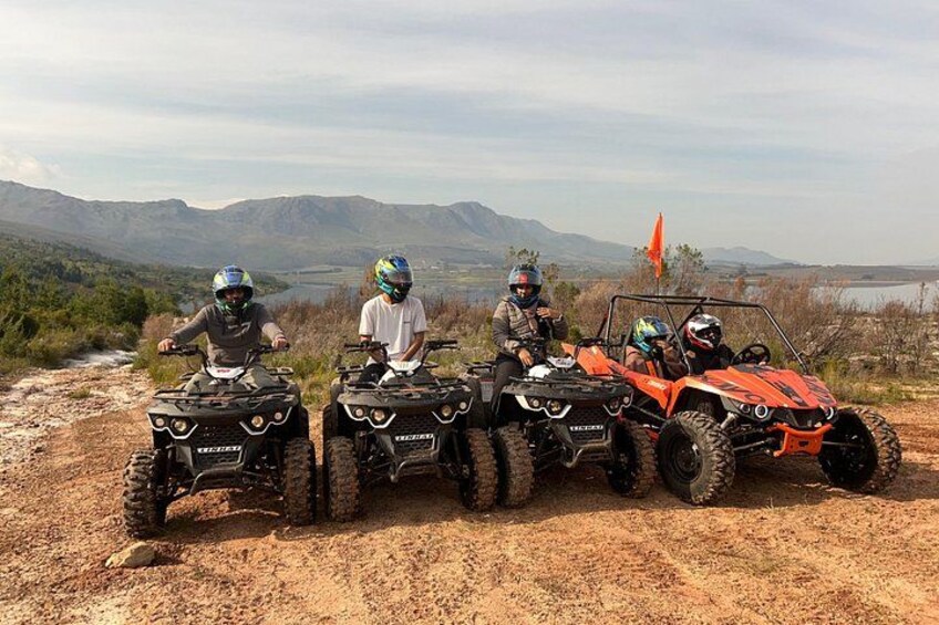 Four off-road vehicles on a dirt path with a mountainous landscape in the background. 5