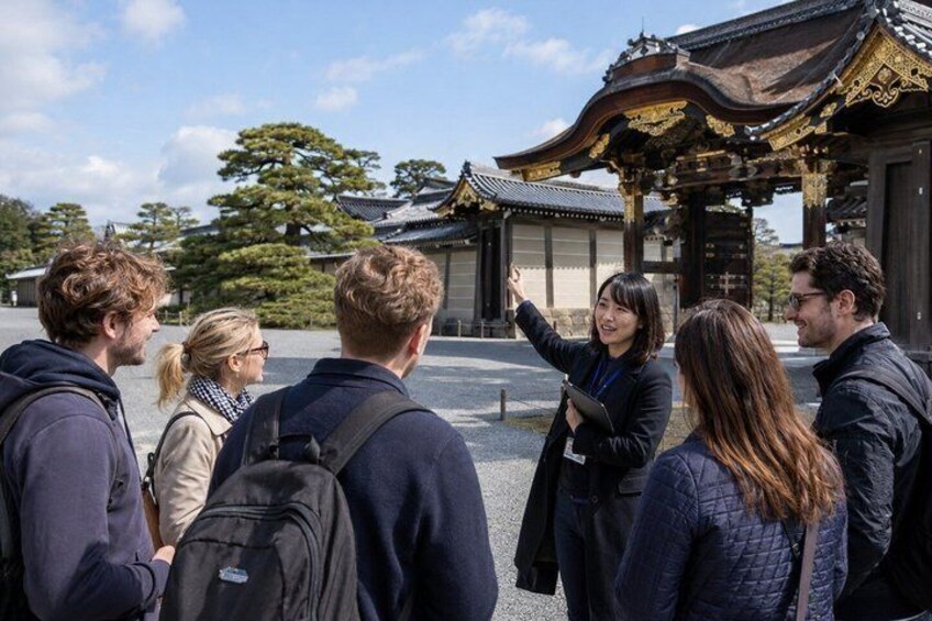 A group of people standing in front of a traditional Japanese building with a curved roof and ornate details. 5