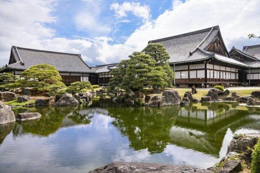 A traditional Japanese garden with a pond, rocks, and a large tree. 4