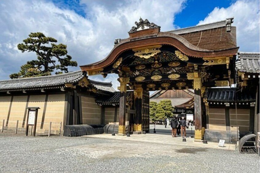 A traditional Japanese gate with intricate woodwork and a stone pathway leading to a building. 3