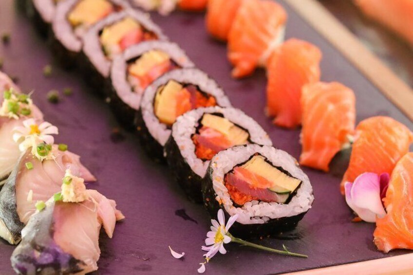 Sushi rolls with salmon and avocado on a purple plate, garnished with flowers. 1