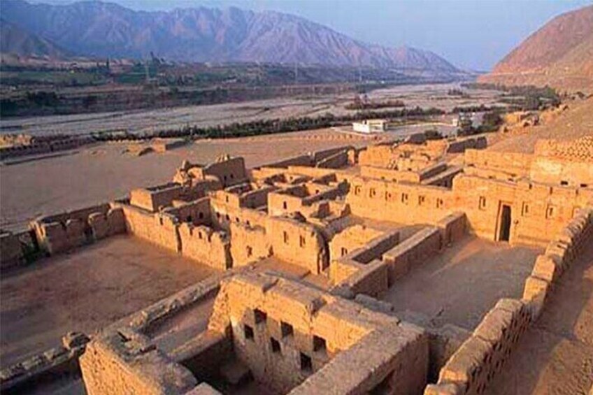 An ancient mud-brick settlement with terraced structures and a river in the background. 3