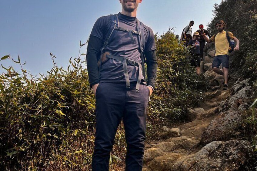 A person standing on a rocky trail with vegetation on either side. 5