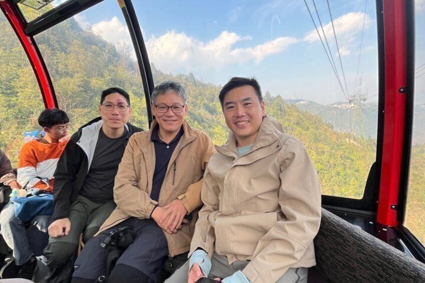 A group of people seated inside a cable car with a mountainous landscape in the background. 3