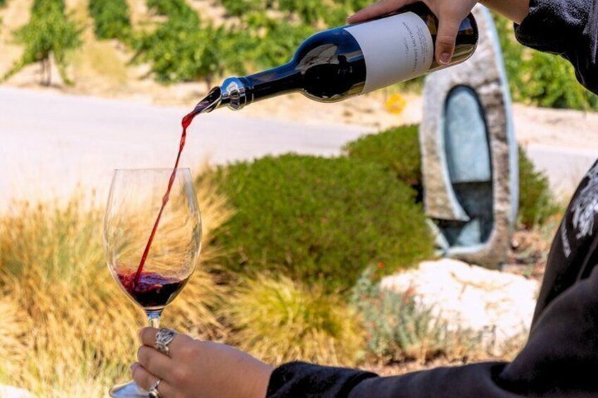 A person pouring red wine into a glass. 3