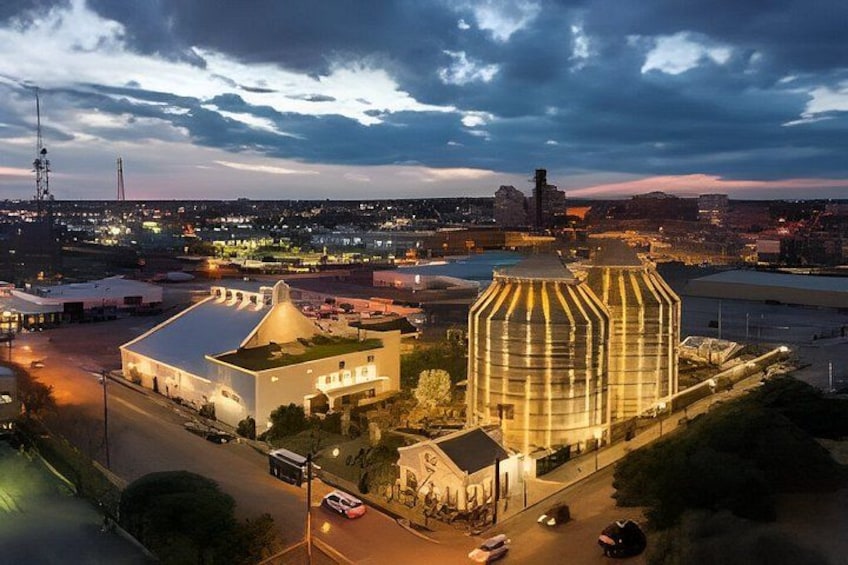 A cityscape at dusk with illuminated buildings, a prominent dome structure, and a river in the background. 3